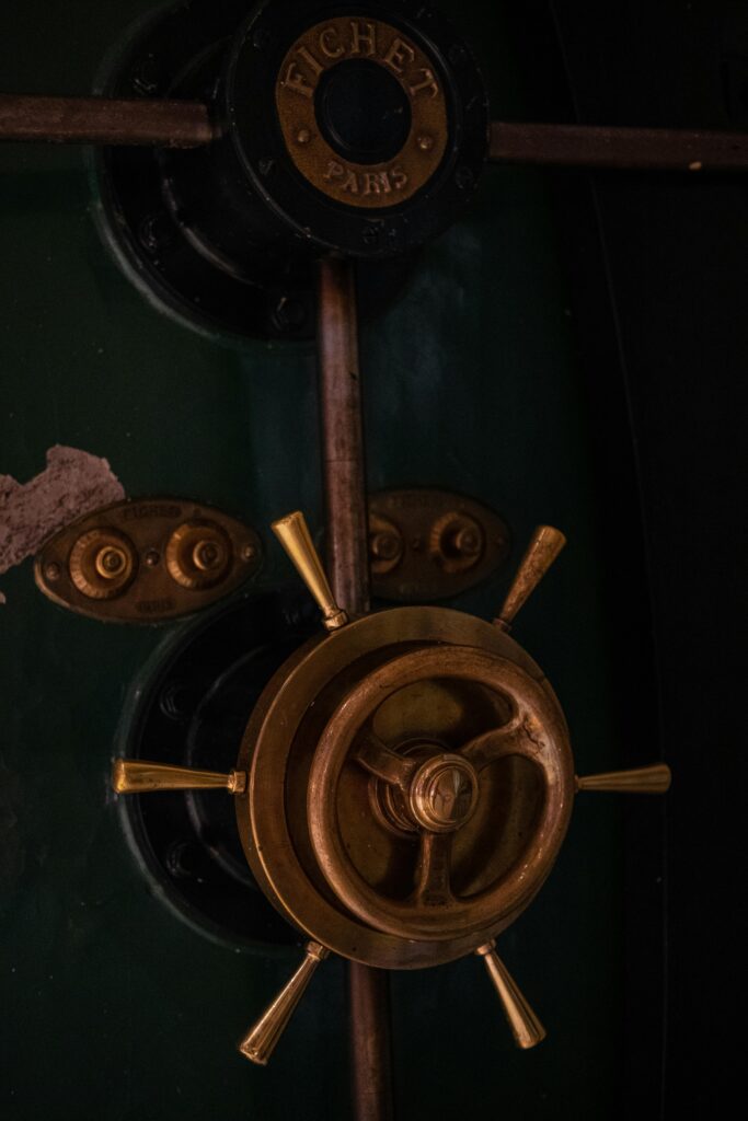 pexels photo 12651886 12651886 Close-up of a vintage safe door with a brass handle and dark green surface.
